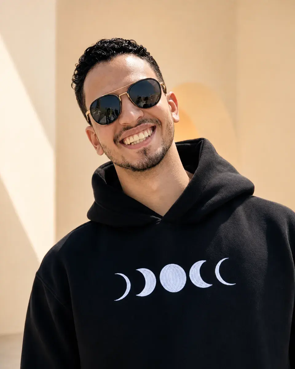 Portrait of Omar smiling in sunglasses and a black hoodie